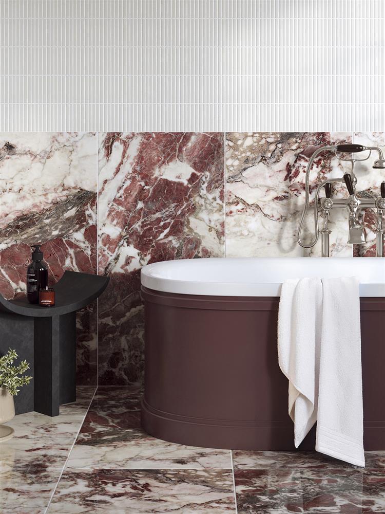 Rich red marble tiles behind a bath with white kit kat tiles above